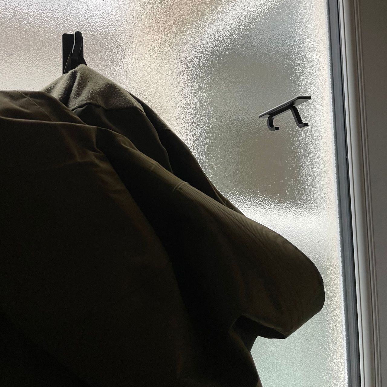 Black self-adhesive hooks falling off the glass on a back door