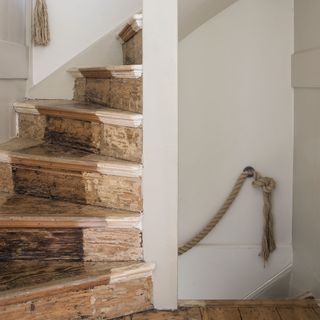 Neutral stairway with distressed wood stairs and rope handrail
