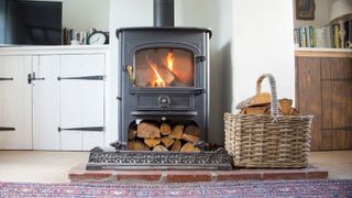 A log burner with wood stacked underneath and a basket filled with more wood to the right of it