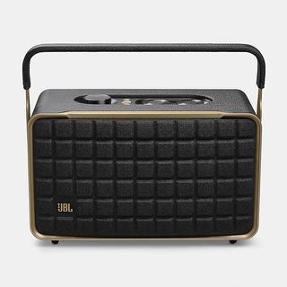 A JBL Authentics 300 speaker. It is black with gold trim, with a pattern made up of squares on the front and controls on top. It also has a handle.