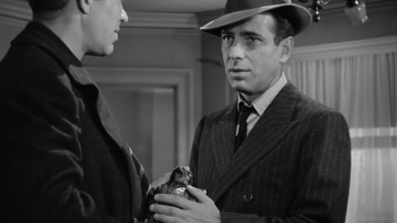 Humphrey Bogart as Sam Spade holding the titular artifact from The Maltese Falcon