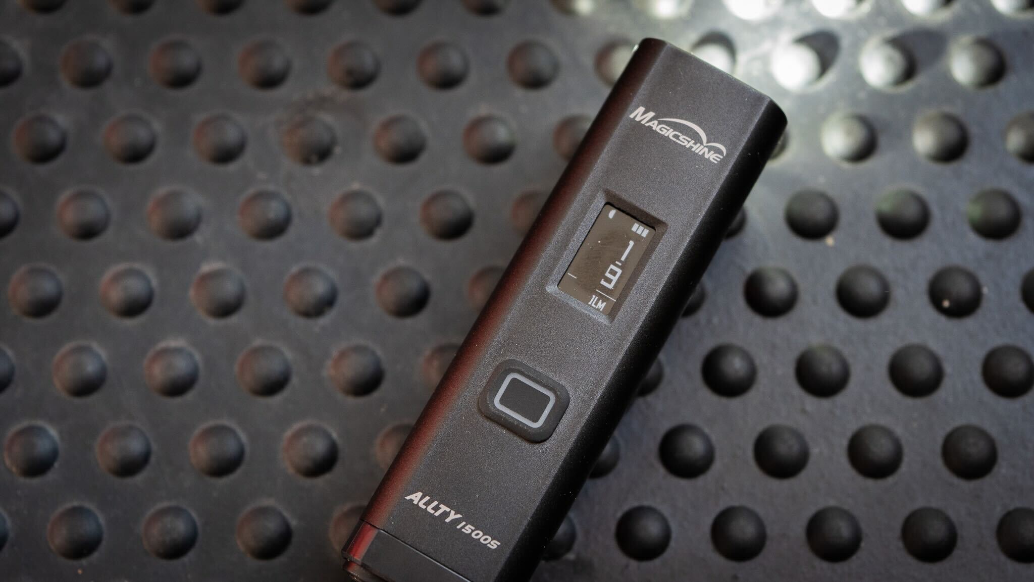 Magicshine Ally 1500s switched on against the background of a texture flooring.