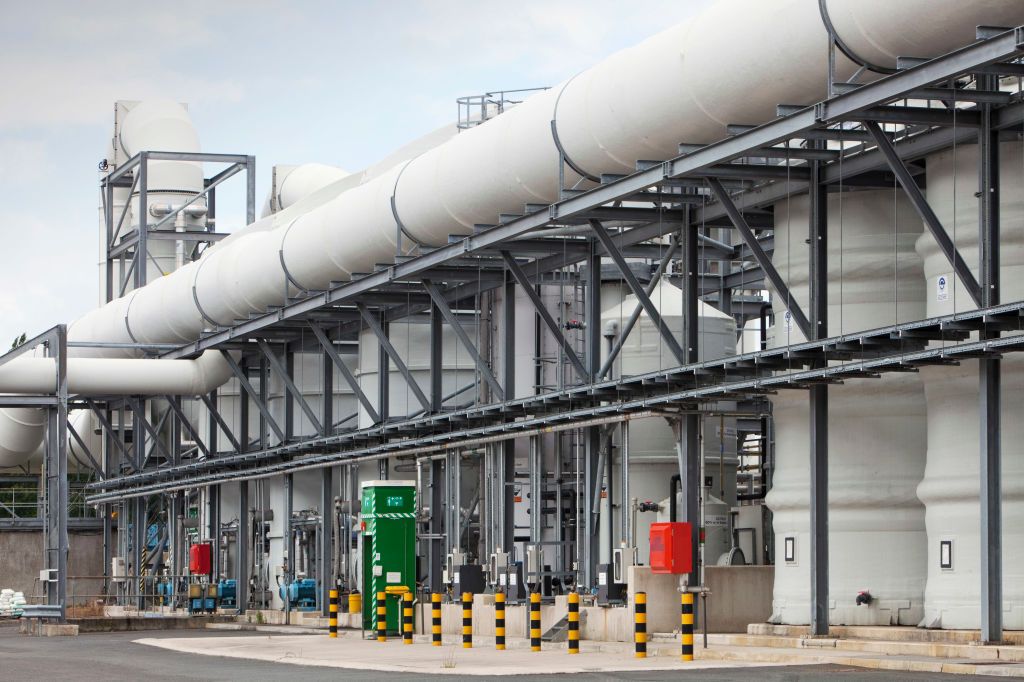 A photo of the outside of Daveyhulme wastewater treatment plant showing a large building surrounded by large white pipes