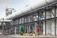 A photo of the outside of Daveyhulme wastewater treatment plant showing a large building surrounded by large white pipes