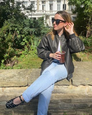 @gracelindsay__ sitting in a park wearing sunglasses and a leather jacket