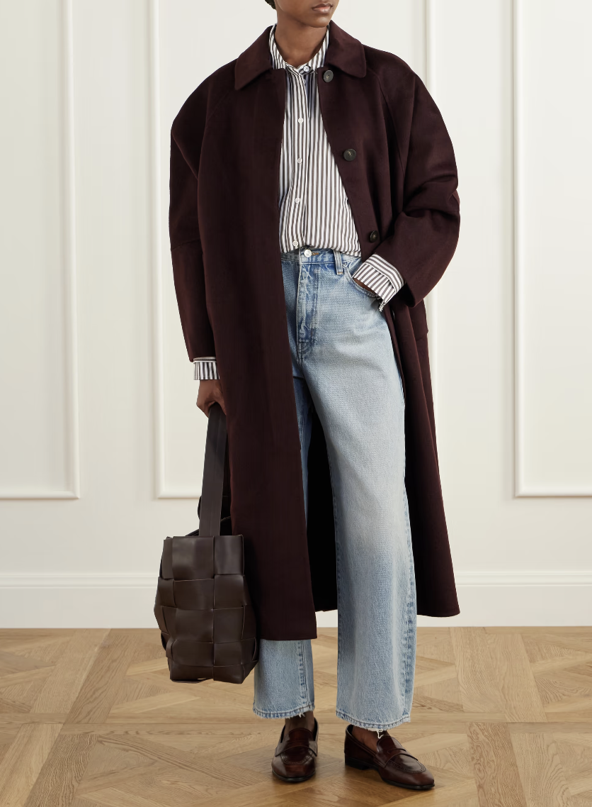 A model in a long maroon coat and jeans