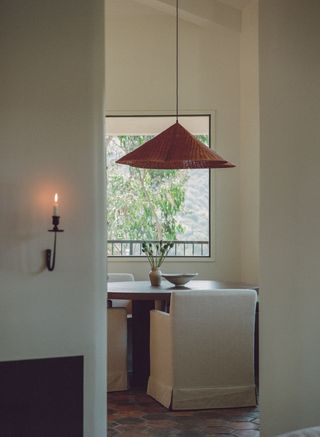 A dining space with a rust orange pendant lamp