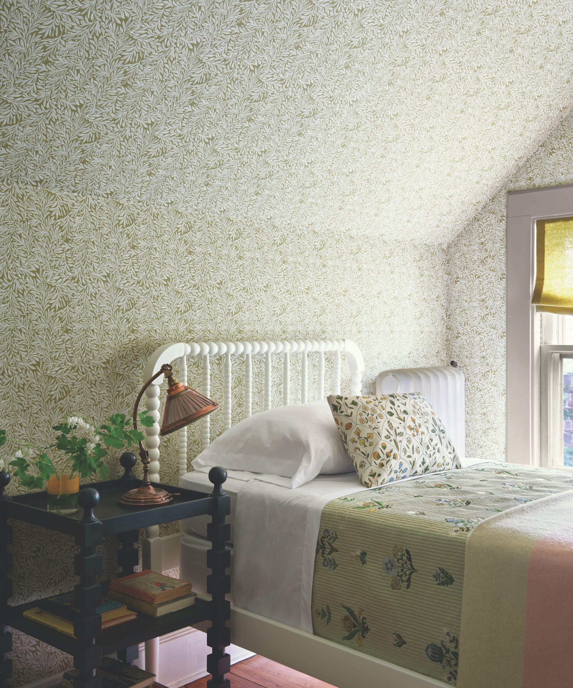 Vintage bedroom with floral wallpaper, single bed, wood nightstand and vase of flowers