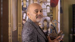 Shoe designer Christian Louboutin poses with one of his creations