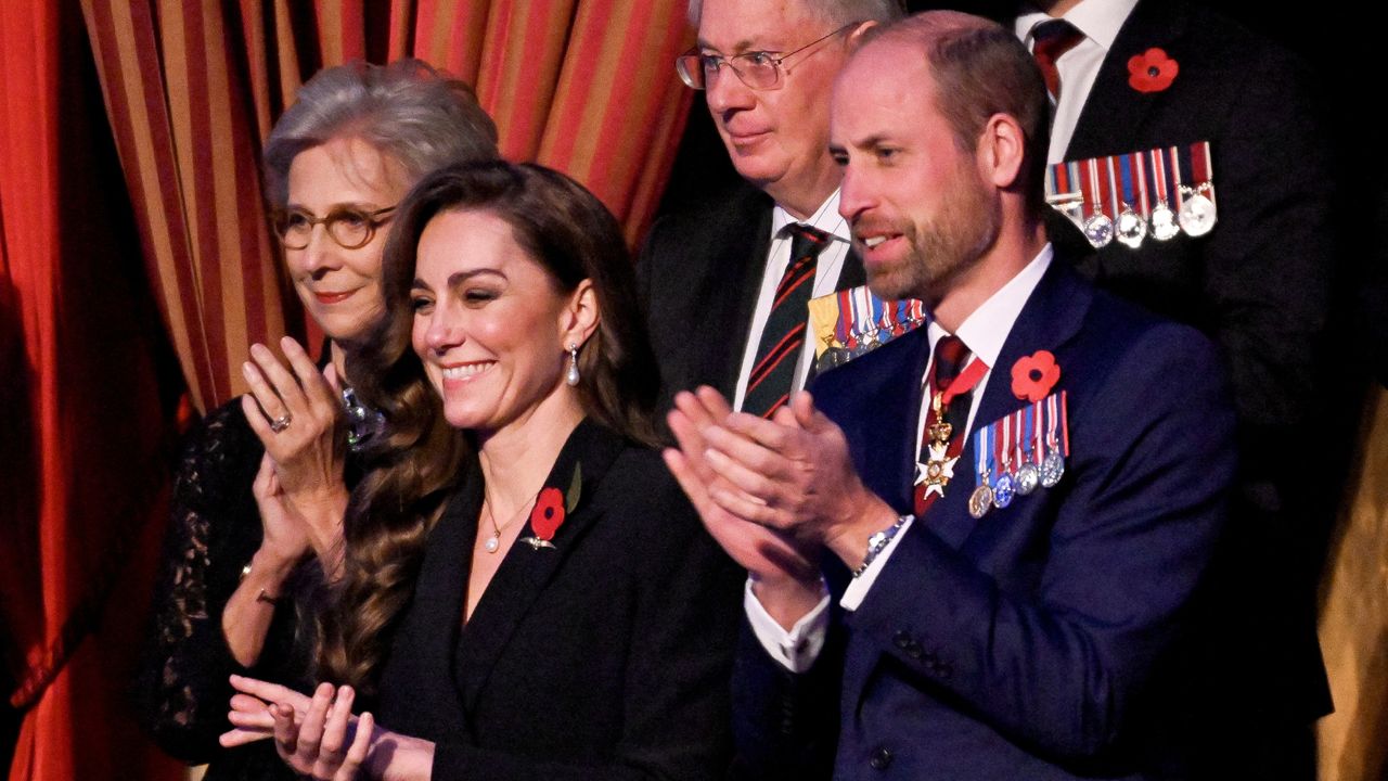 Kate Middleton wearing a black dress and Prince William wearing a blue suit and military medals clapping and smiling during the Festival of Remembrance concert