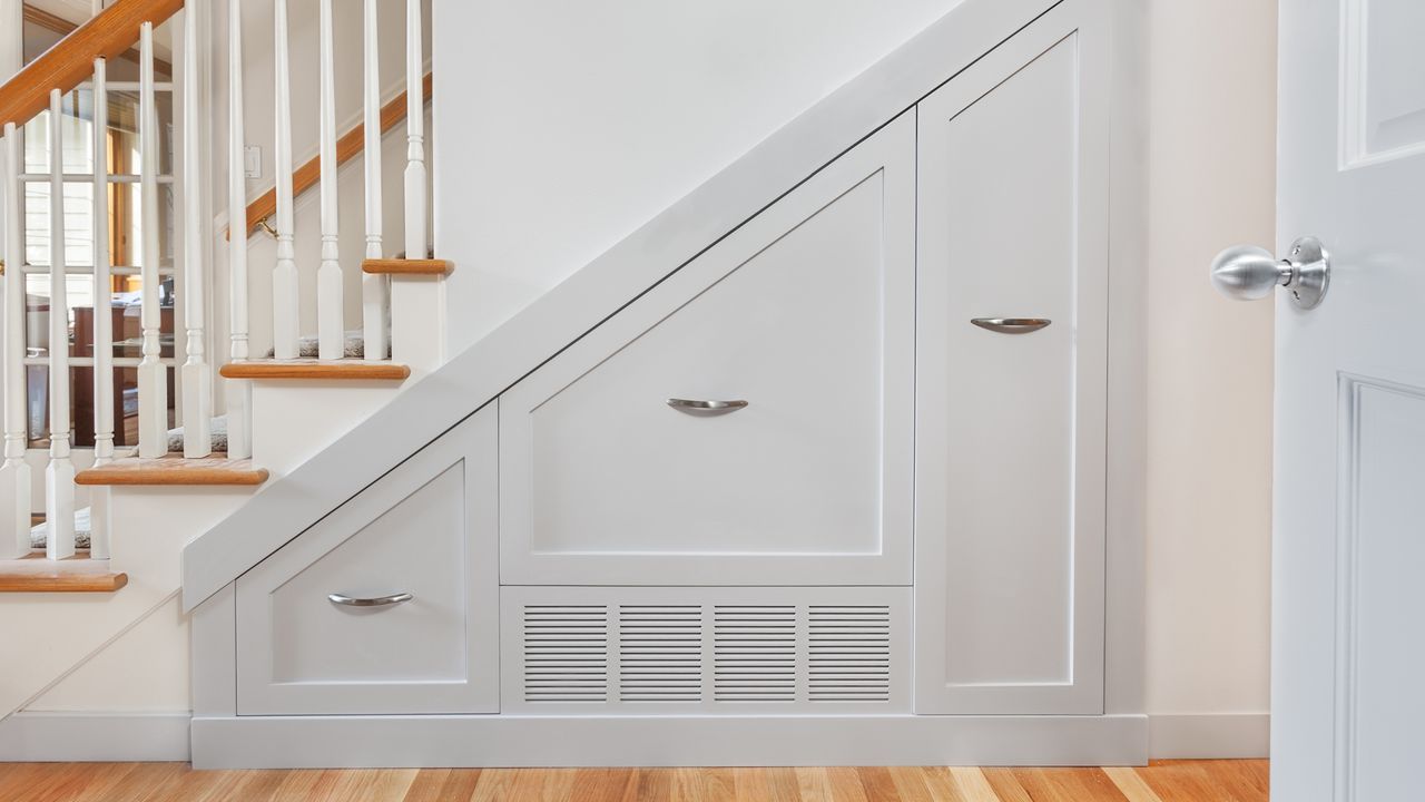 An image of a white and pine stair case with gray storage drawers underneath the stair case