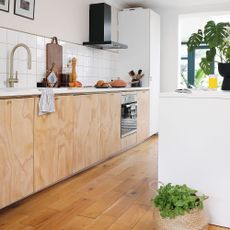 Run of plywood covered units in a white kitchen