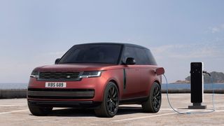 A red Range Rover PHEV plugged into a charger