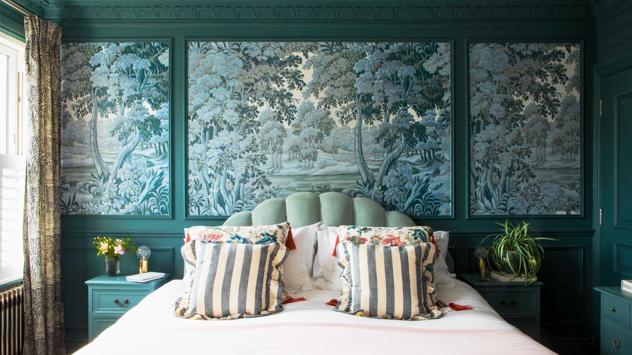 A teal-painted bedroom with wall moulding and wallpaper mural panels