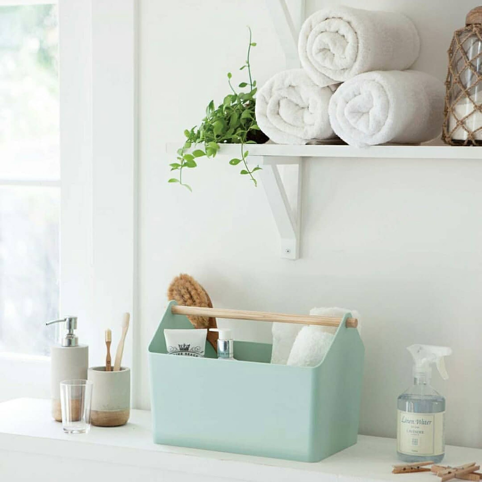 Caddy kamar mandi berwarna hijau mint untuk menyimpan kebutuhan kamar mandi kecil, dengan gulungan handuk putih di rak.