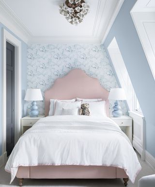 bedroom with pink headboard and blue print wallpaper in attic room
