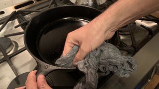 Cast iron skillet being seasoned with oil
