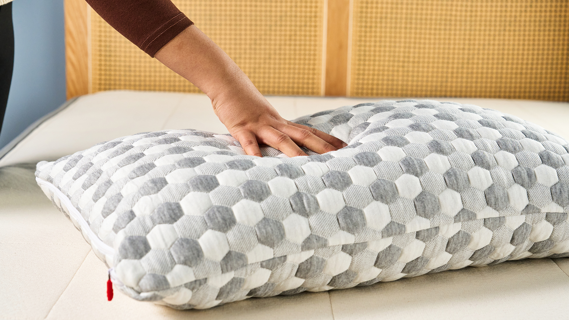 A woman's hands get ready to fold a pillow in half to test if it needs replacing.
