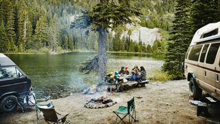 Friends sharing a meal while camping by lake