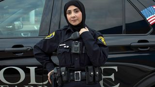Female policewoman standing in front of police car