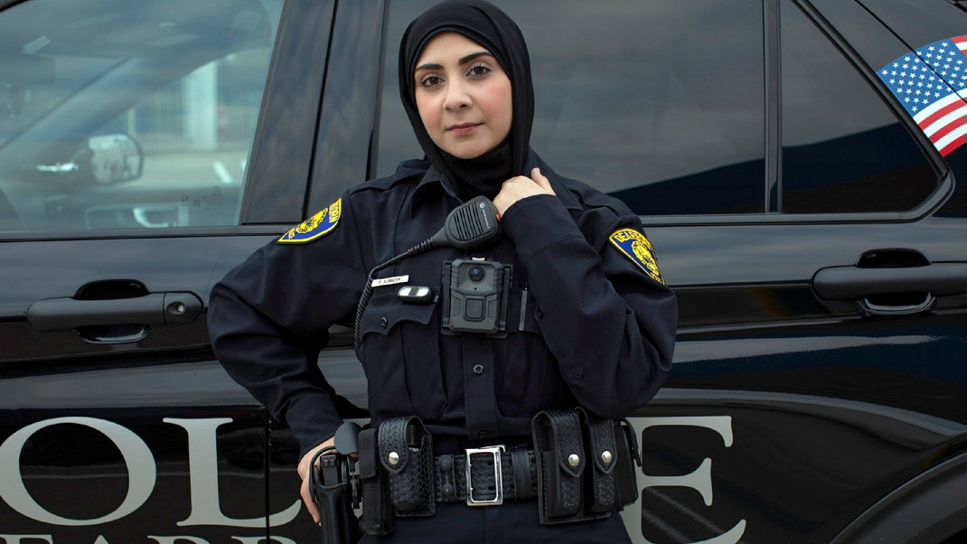 Female policewoman standing in front of police car