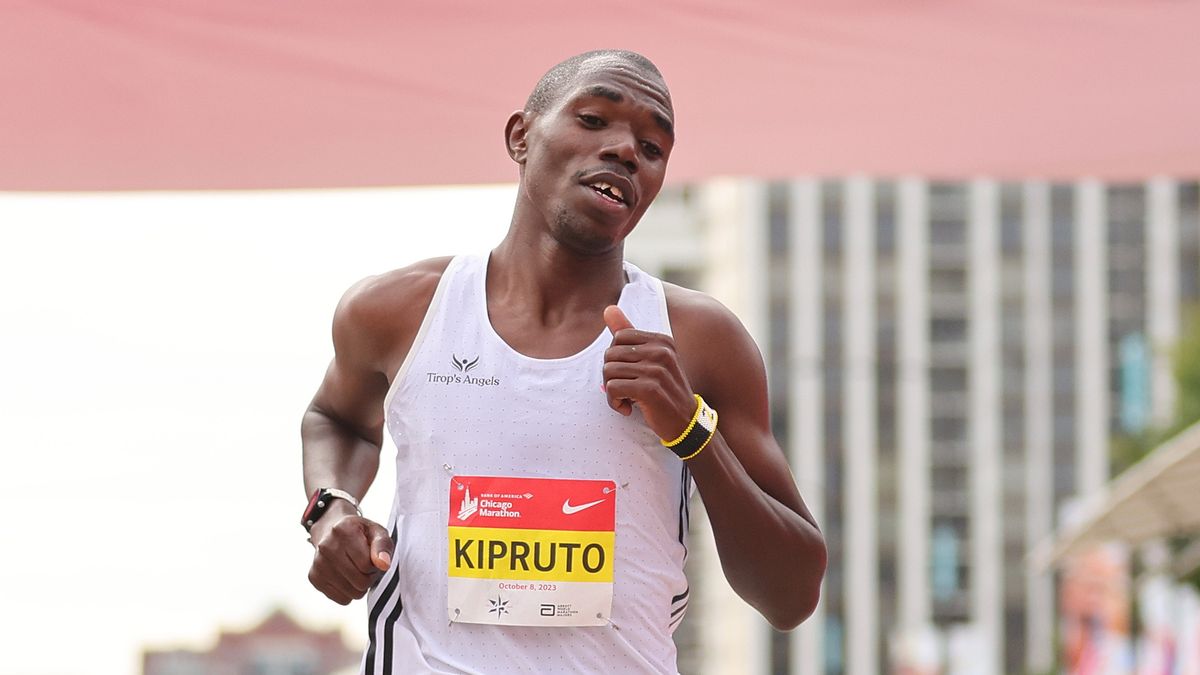 Kipruto of Kenya, wearing a white running vest, crosses the finish line ahead of the 2024 Chicago Marathon