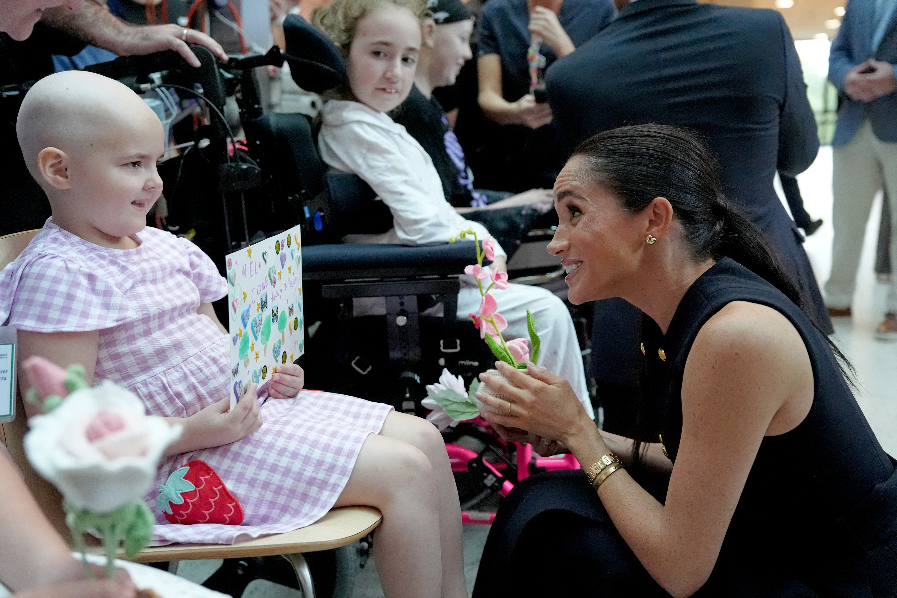 Meghan Markle bending down and talking to a little girl