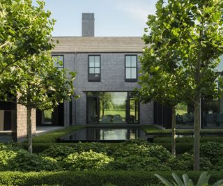 Back view of a property with lush trees, hedges and modern pool
