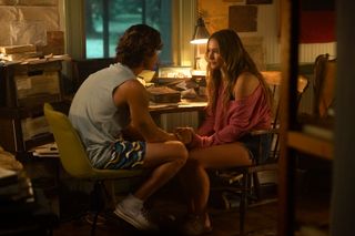 Chase Stokes as John B and Madelyn Cline as Sarah Cameron, facing each other while sitting in chairs in a home office, in episode 408 of Outer Banks.