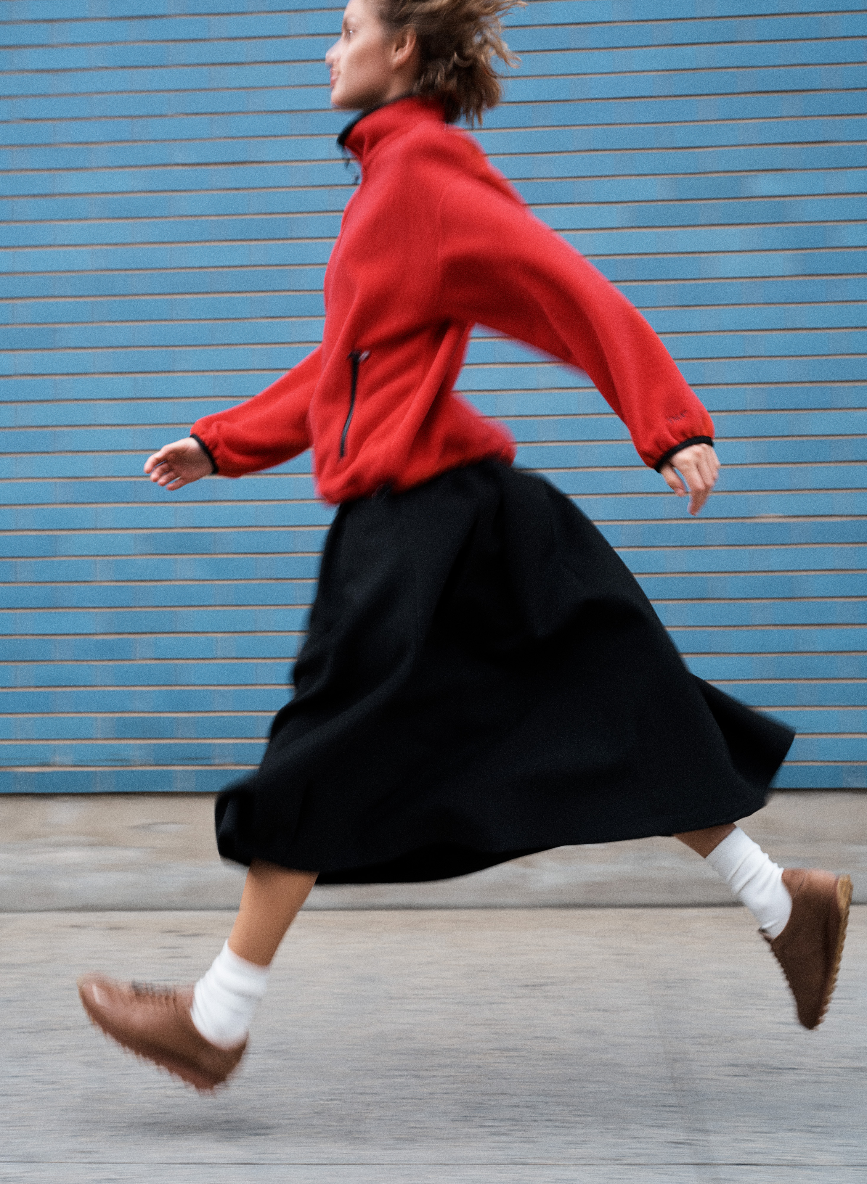 a model wears her aritzia x nike sneakers with a fleece and skirt