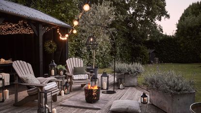 decking area with festoon lights and fire pit at night