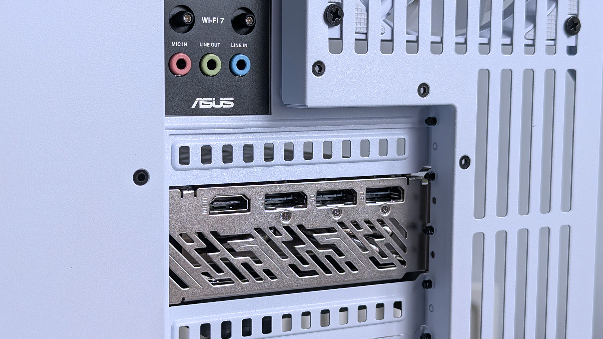 Close-up of an iBUYPOWER RDY Trace X R01 computer's rear panel showing an Asus logo, Wi-Fi 7 module, colored audio ports, and multiple HDMI outputs.