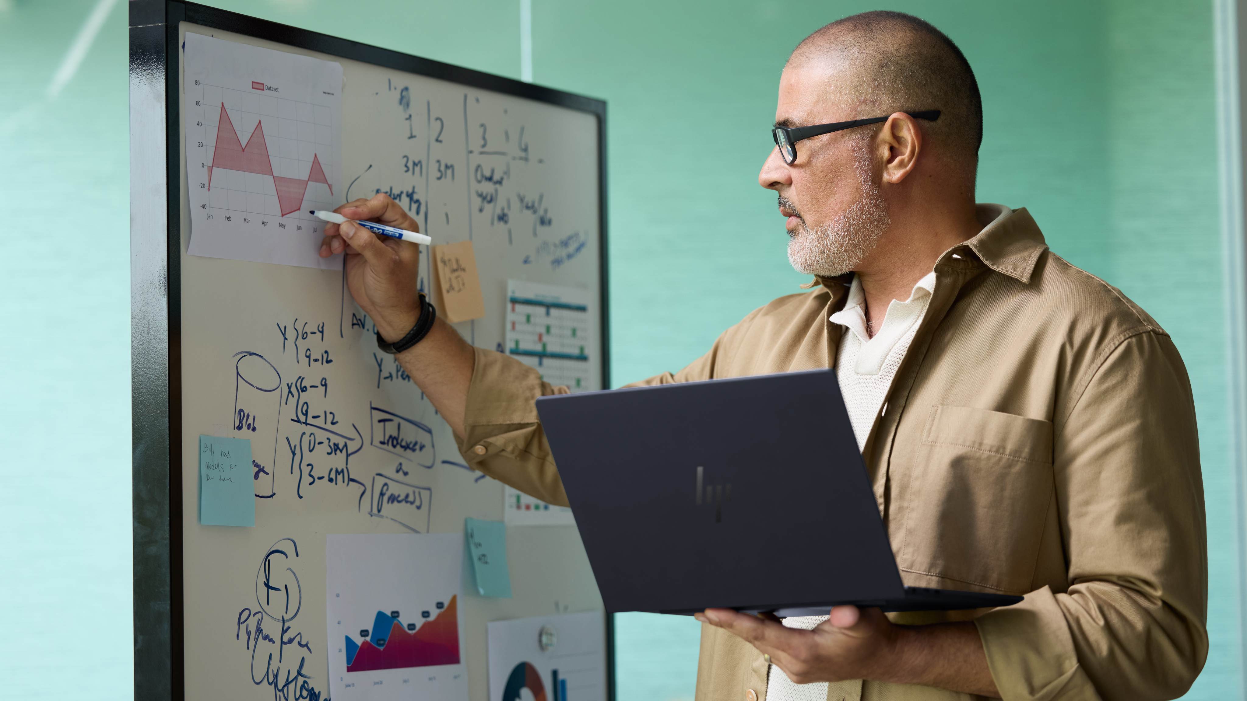 A person standing and holding the HP EliteBook Ultra 14 (G1i) while drawing on a whiteboard.