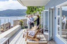 Real estate agent showing a mature couple a new house. The house is contemporary. All are happy and smiling and shaking hands. Waterfront can be seen in the background