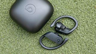 Hero image for best sport headphones showing the Beats Powerbeats Pro with charging case on on green background