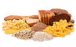 A plate of various carbohydrate rich foods, including bread, pasta and rice