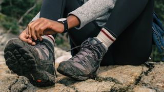 woman putting on a pair of boots over some hiking socks
