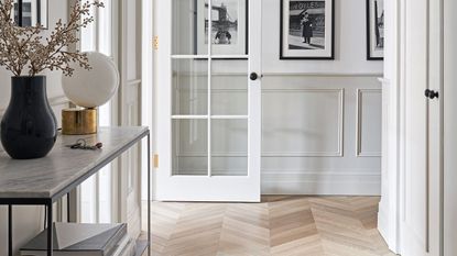 Small hallway ideas with wood floor and white walls with black and white photographs on them.