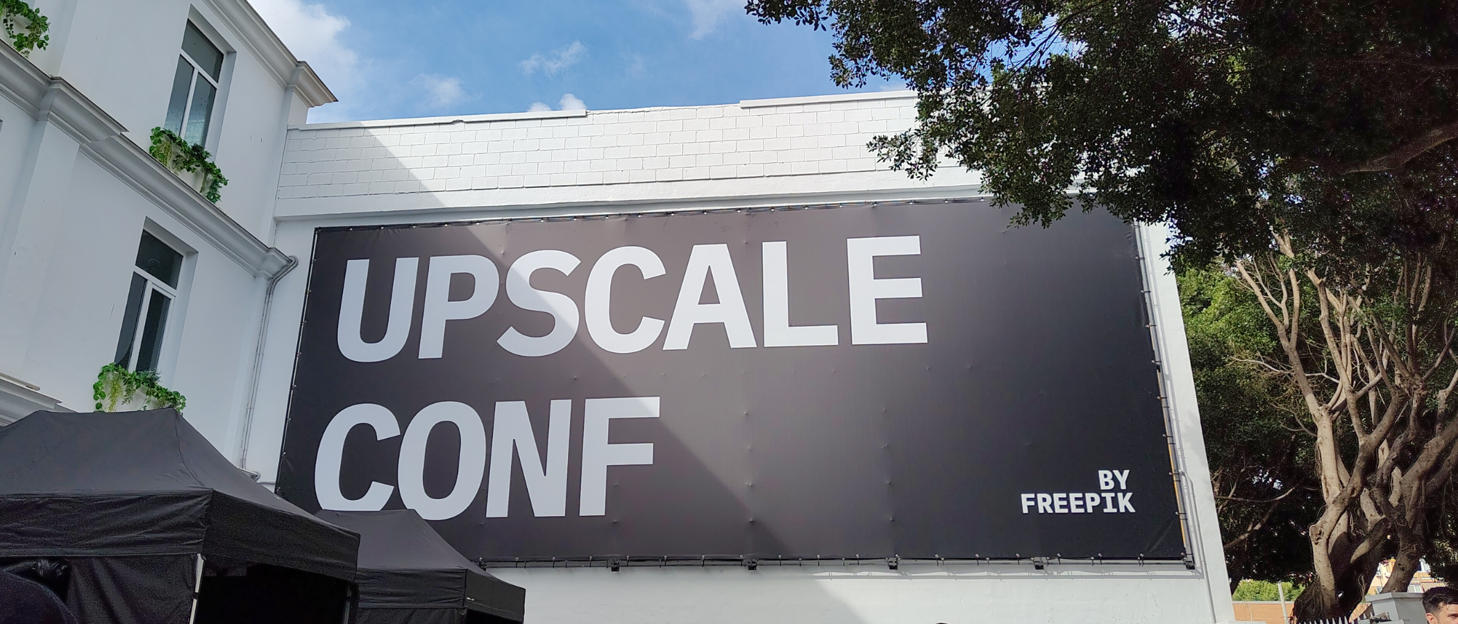 The Freepik Upscale Conf banner on a white building in Malaga