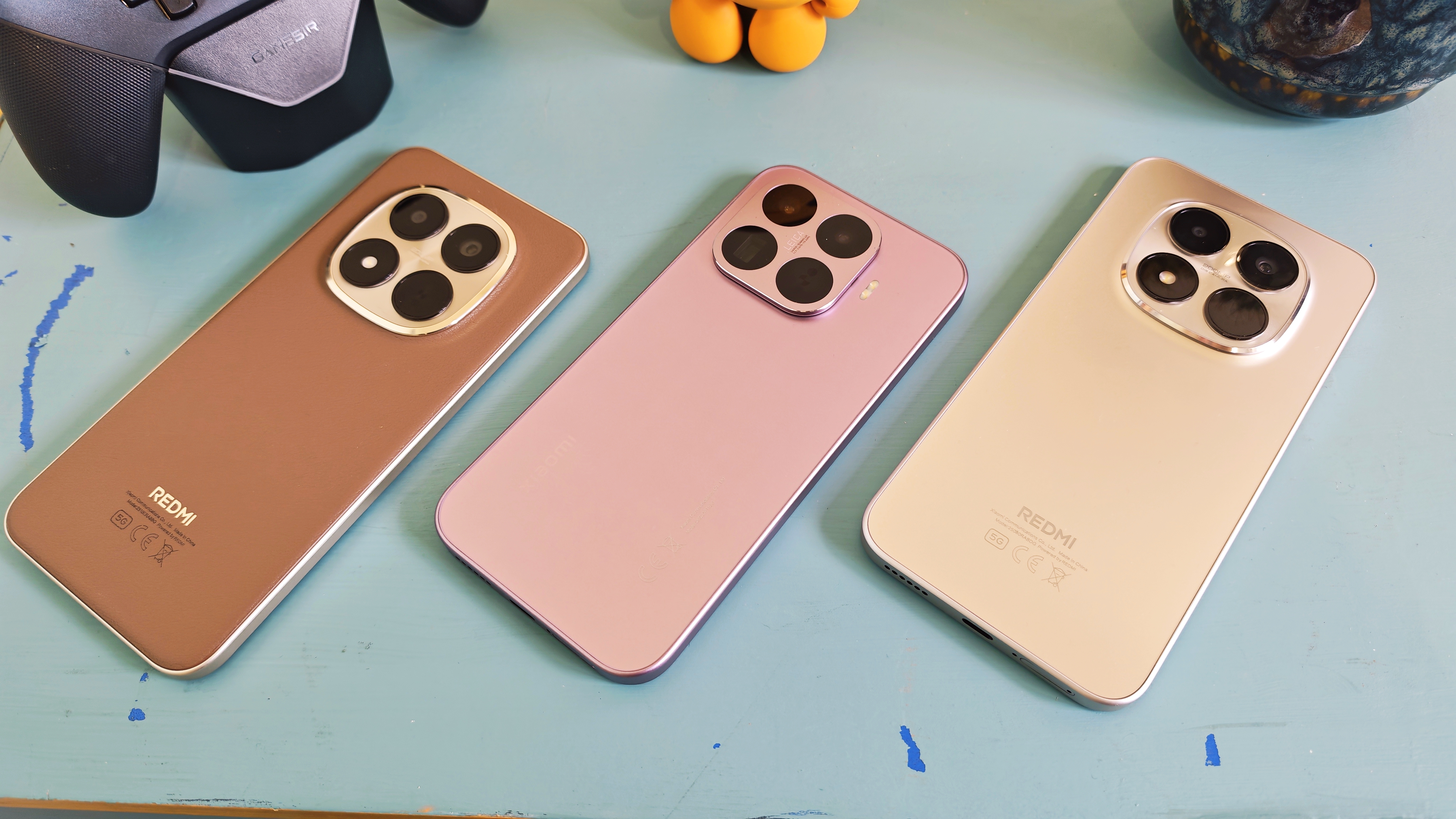 Three Xiaomi and Redmi phones on a blue-green table