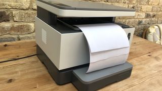 HP Neverstop Laser MFP 1202nw on a wooden desk with paper loaded