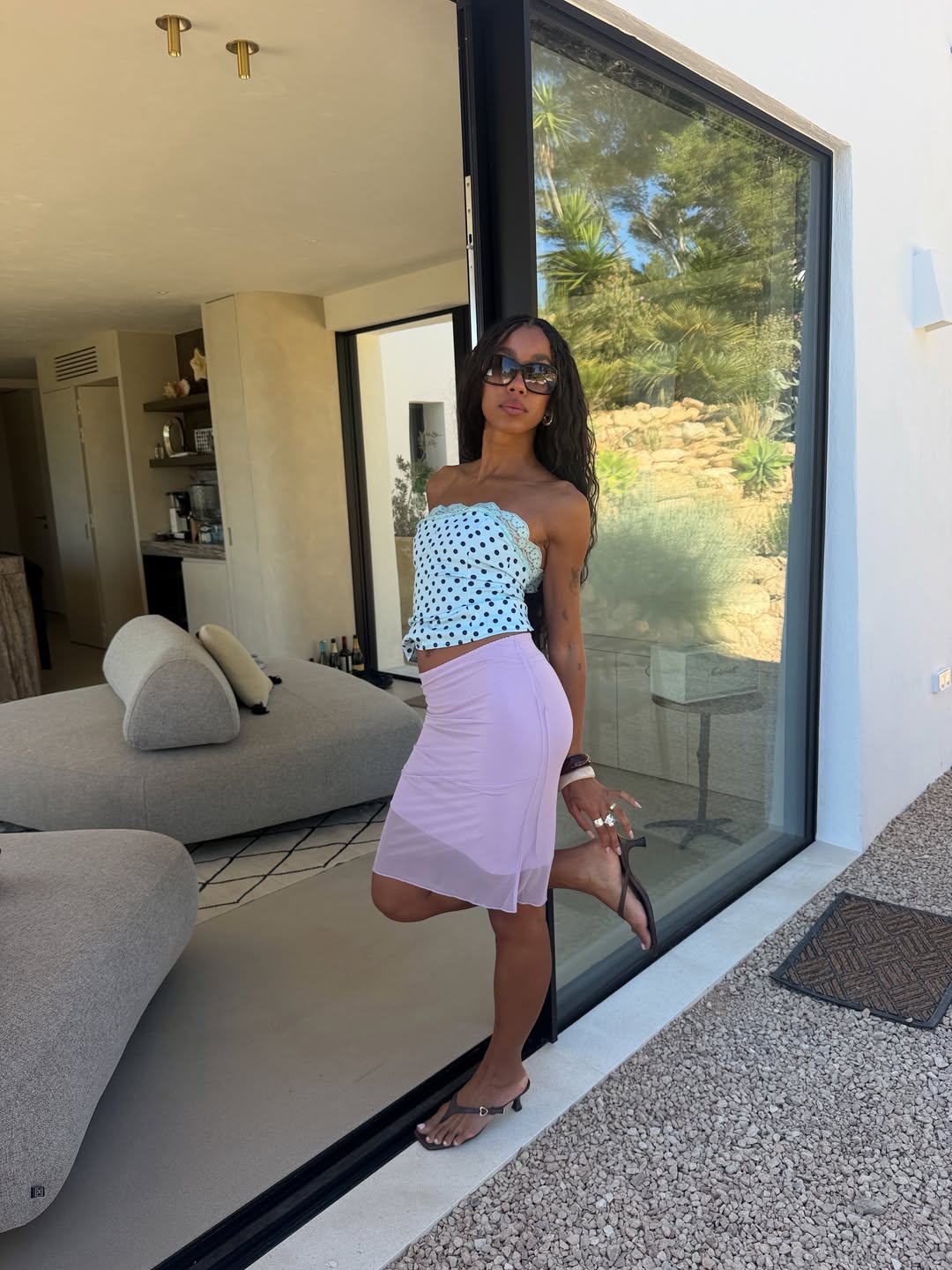 amaka.hamelijnck wears a blue polka dot top, pink knee skirt and brown thong sandals