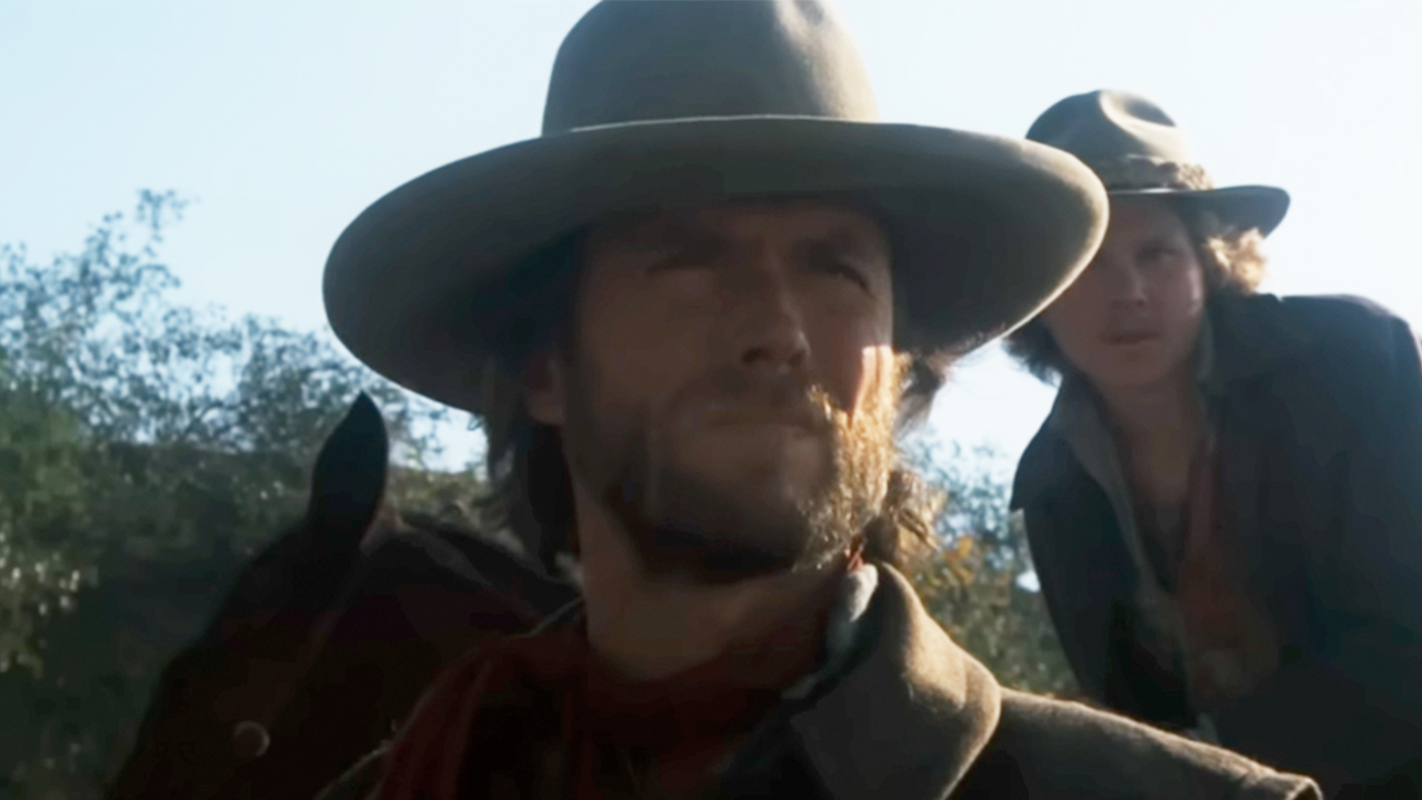 Clint Eastwood with a hat on, with Sam Bottoms on a horse behind him in The Outlaw Josey Wales