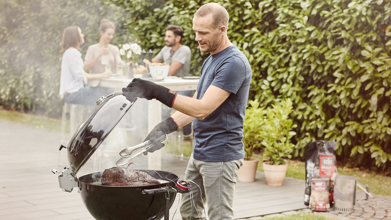 Man slow cooks a joint of meat on a charcoal bbq