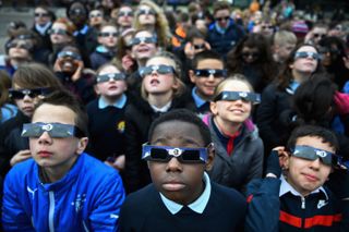 Onlookers observe a partial solar eclipse in Glasgow in 2015, while wearing solar viewing glasses. When the moon completely covers the sun's disk, it is safe to remove solar viewing glasses.