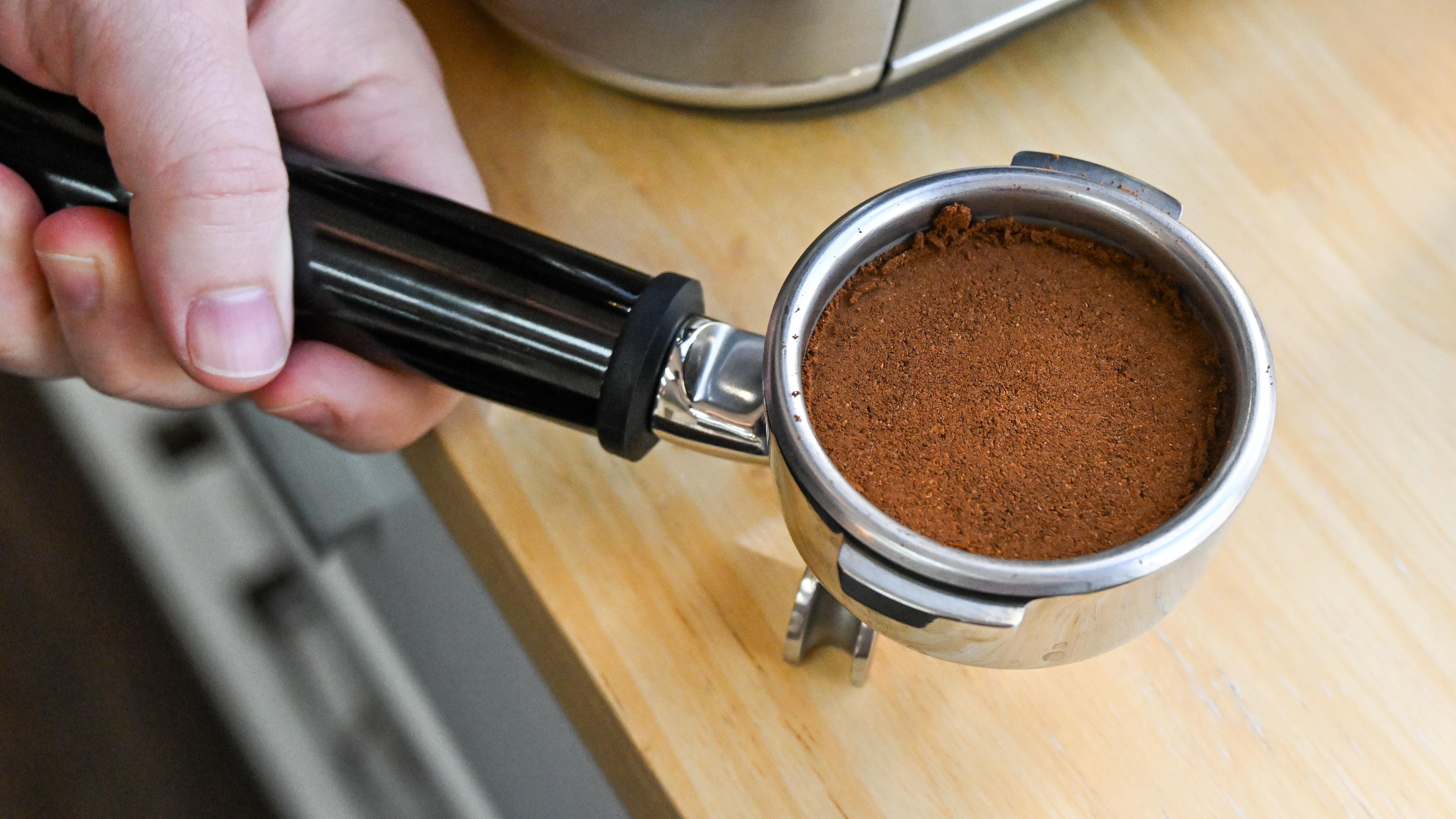 A top down view of the portafilter from the Breville Oracle Jet coffee machine, filled with ground coffee and neatly tamped.