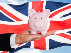 Businessman Holding Piggybank In Front Of British Flag