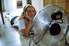 teen girl creates her personal oasis on the floor, listening to music through wireless headphones in front of a cooling fan