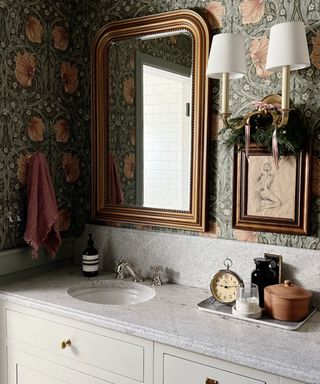 wallpapered bathroom with a marble vanity and christmas foliage decor