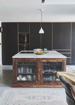 A kitchen island in vintage style with fluted glass doors and black timber cabinets behind